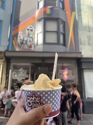 An gelato in a tub with a spoon held up in front of the Boho Gelato shop front in the Poole Valley, Brighton